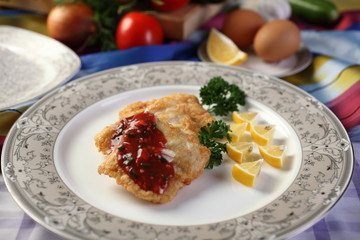 Fried fish with garlic on plate with lemon and spices.