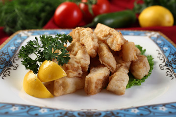 Perch fillet in pastry on a plate with slices of lemon and herbs.