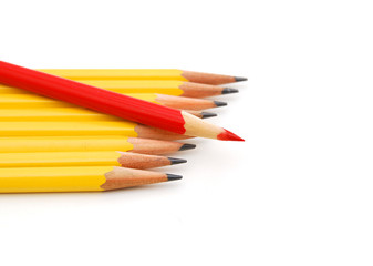 Yellow pencils and one red crayon standing out from the crowd. Isolated on white.