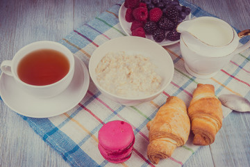 Organic vegetarian breakfast - oatmeal with berries, milk, tea and croissants