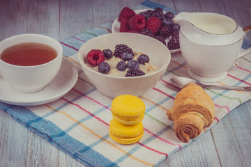 Organic vegetarian breakfast - oatmeal with berries, milk, tea and croissants