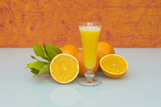 Zumo de naranjas recien exprimido y naranjas frescas con hojas