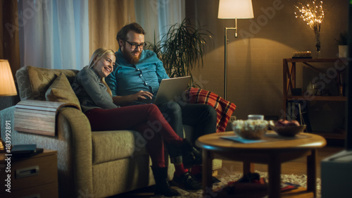 Friend And Boyfriend Sitting On A Sofa With Laptop His Knees Friend And Boyfriend Sitting On A Sofa With Laptop His Knees Watching Videos