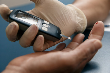 doctor or nurse performing glycemia examination with a digital measuring device.