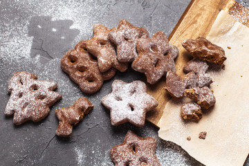 Christmas cookies with powdered sugar on a wooden, cutting board on a gray background