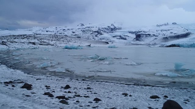 Aerial footage of blue iceberg in frozen lagoon, Fjallsárlón Iceland