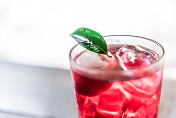 A glass of red water with a longan inthe glass white background