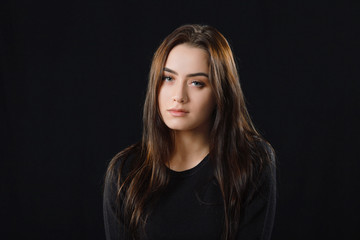 Low key portrait of young adorable caucasian woman in black sweater on dark background. Facial expressions and emotion concept.