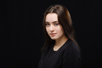Low key portrait of young adorable caucasian woman in black sweater on dark background. Facial expressions and emotion concept.