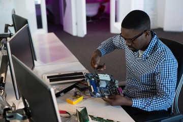 Computer engineer repairing motherboard at desk