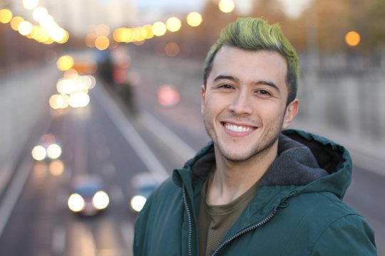 Head shot of handsome green haired guy smiling in the city 