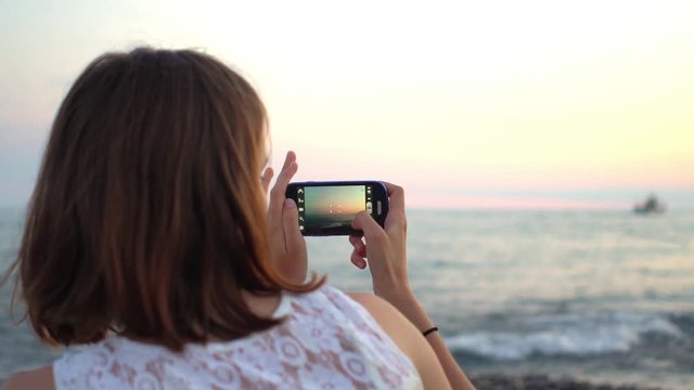 Young hipster woman taking pictures with smartphone on the beach
