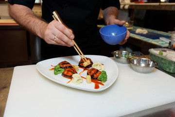 Chef is decorating a dish with chopsticks