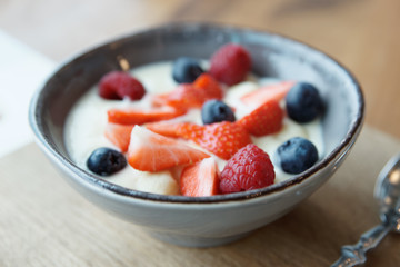 Cream and berries dessert in deep china plate