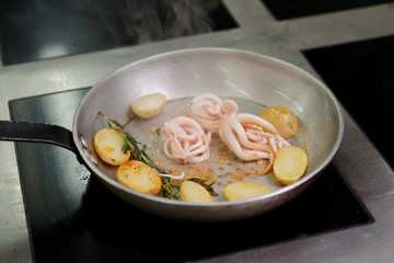Octopus and potatoes being fried on pan