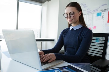 Female executive using laptop at desk