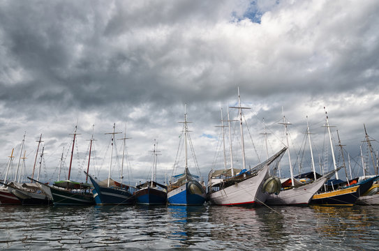 Numerous lined up boars at anchor under stormy sky