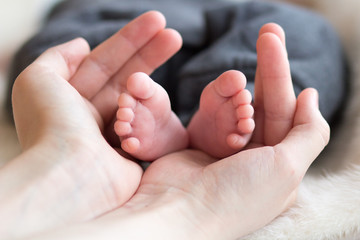 Mother's hands holding a little child's feet