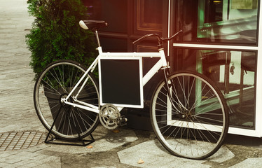 the bike is on the street. a blank black banner. decor and design.
