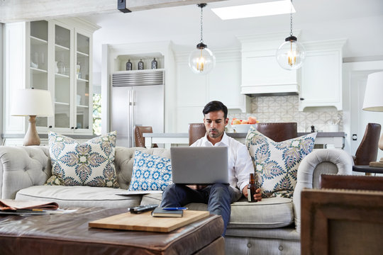 Hispanic businessman working on laptop in living room at home