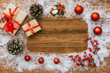 christmas background with decorations and gift boxes covered with snow over rustic wooden background. top view