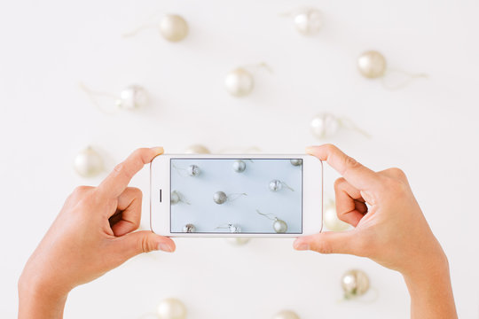 Woman using phone camera take a picture of Christmas ball