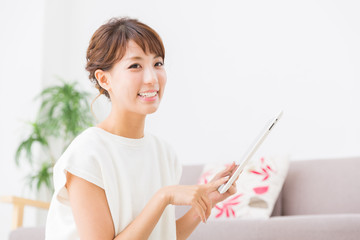 部屋でタブレットを見る女性