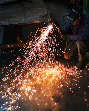 Welder kneels as he works on sheet metal