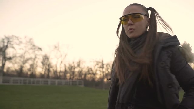 Attractive young hipster woman in a stylish look dancing freestyle on urban background at sunset or dusk