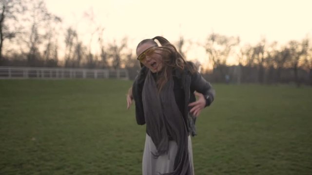 Attractive young hipster woman in a stylish look dancing freestyle on urban background at sunset or dusk