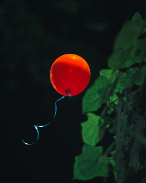 Red balloon floating in the night.