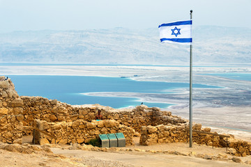 Israeli flag with the ruins on Masada with the Dead Sea on the background