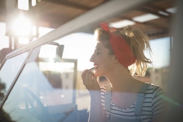 Woman applying lipstick in a car