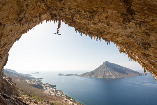 Climber hanging from a stalactite high up on a cave roof