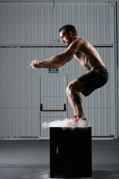 Fit man jumping on a workout box in the gym