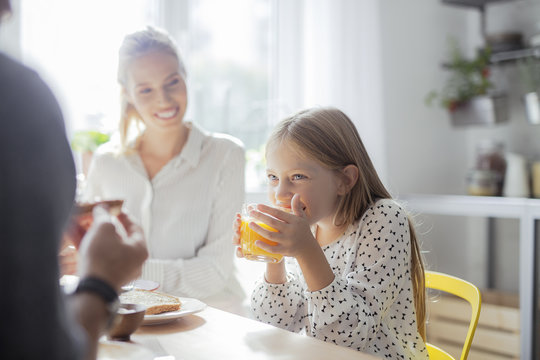 Cute Girl Drinking Juice and Having Breakfast With Her Parents