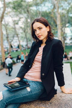 Woman holding a digital device outdoors
