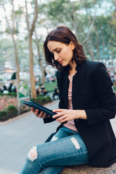 Woman holding a digital device outdoors