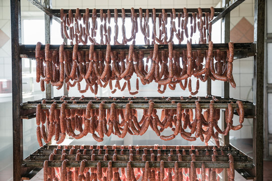 Many linked sausages hanging on mobile rack
