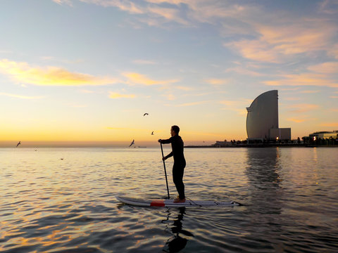 Man doing paddle surf at sunrise, Barcelona beach