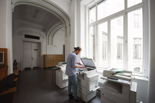 Male student using copymachine in public library