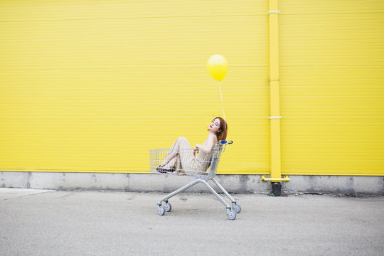 Young woman standing against a yellow wall and holding the balloon