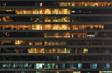 Photo sur Plexiglas construction de la ville immeuble de bureaux la nuit. Tard dans la nuit au travail. Immeuble de bureaux en mur-rideau de verre