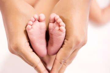 Parent holding in the feet of newborn baby.