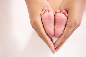 Parent holding in the feet of newborn baby.