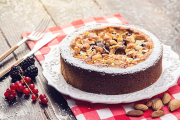 Homemade Christmas or New Year holiday berry pie with nuts on wooden table background. Concept of festive desserts