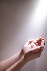 Hands under the glowing light ready to recieve Grace of God. Fervent prayer concept