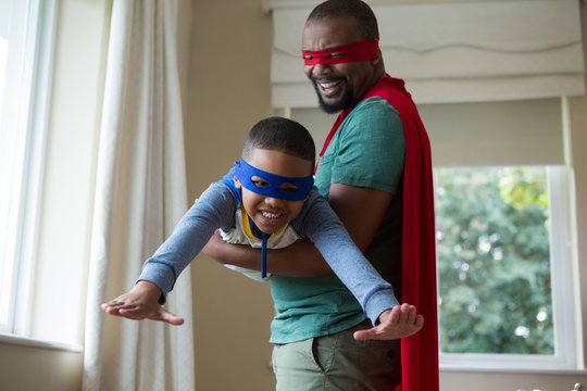 African american son and father pretending to be a superhero at home