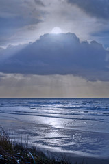 Moon in sky over ocean landscape with silver blue reflection in water/ Moon seascape in Newport, Oregon