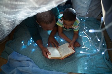 Father and son reading book in bedroom